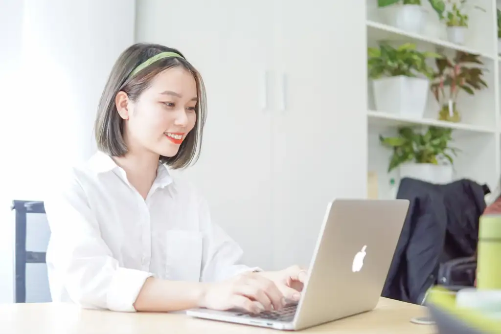 Young woman smiling while working on laptop ready to start her SEO career